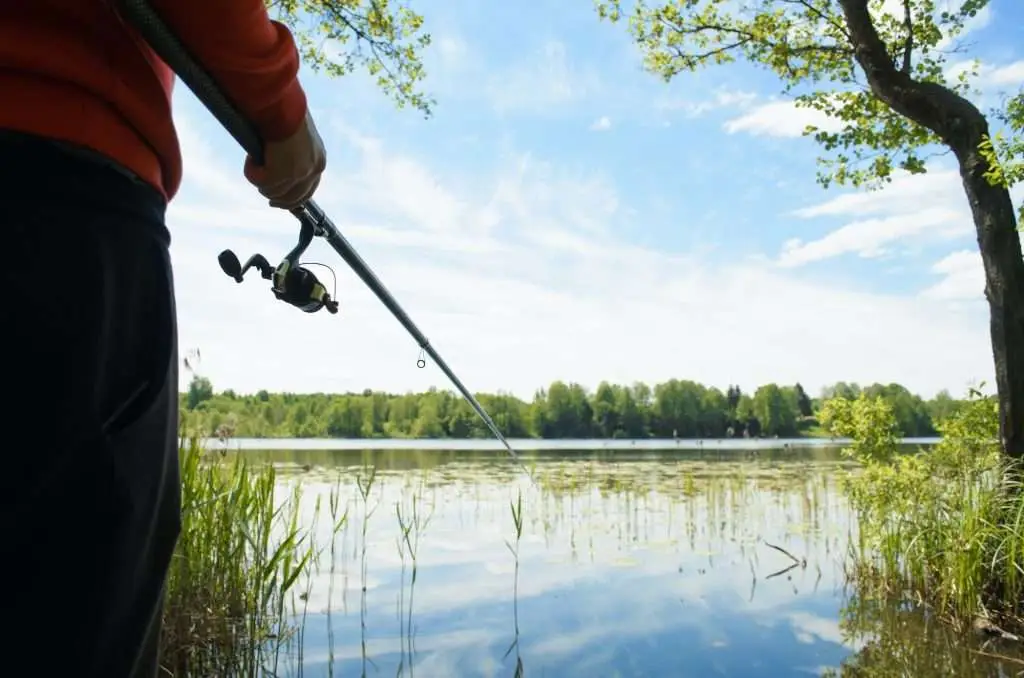 Fishing on the lake. Fisherman holding a fishing rod outdoors close-up. Fishing on a wild lake