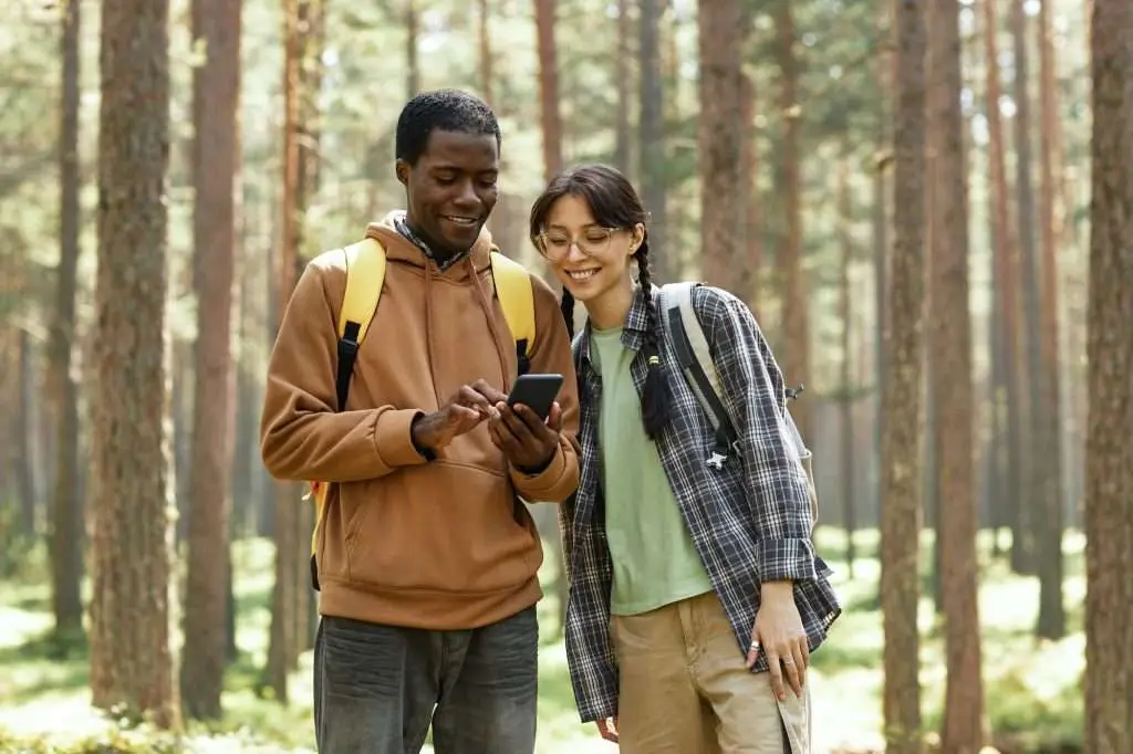 Multiethnic couple using mobile phone in forest