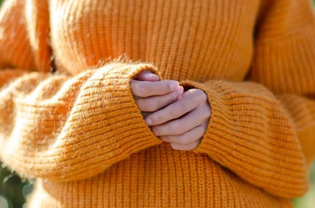 Young woman in cozy jumper in the mountains. Fall fashion. Active lifestyle. Autumn outdoor.