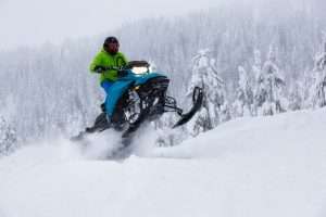 Adventurous Man Riding a Snowmobile in white snow