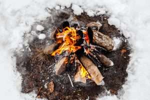 Campfire burns in the snow in the woods.. campfire burning in cold winter. Snow, forest and fire