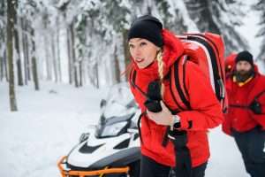 Paramedics from mountain rescue service provide operation outdoors in winter in forest.