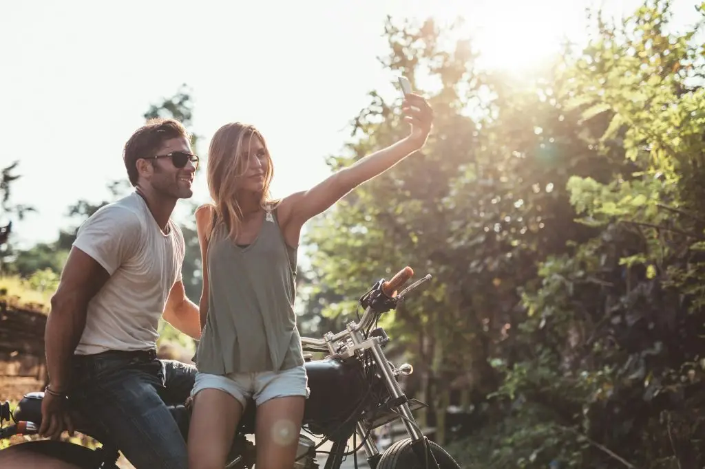 Couple taking a selfie on road trip with motorcycle