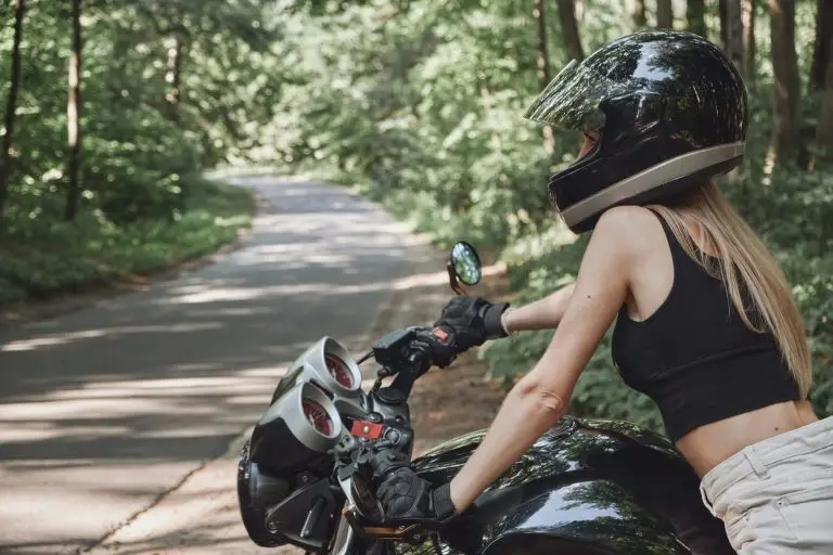 Young woman biker in a helmet drives a motorcycle on a forest road, travels alone. motorcycle routes Ontario