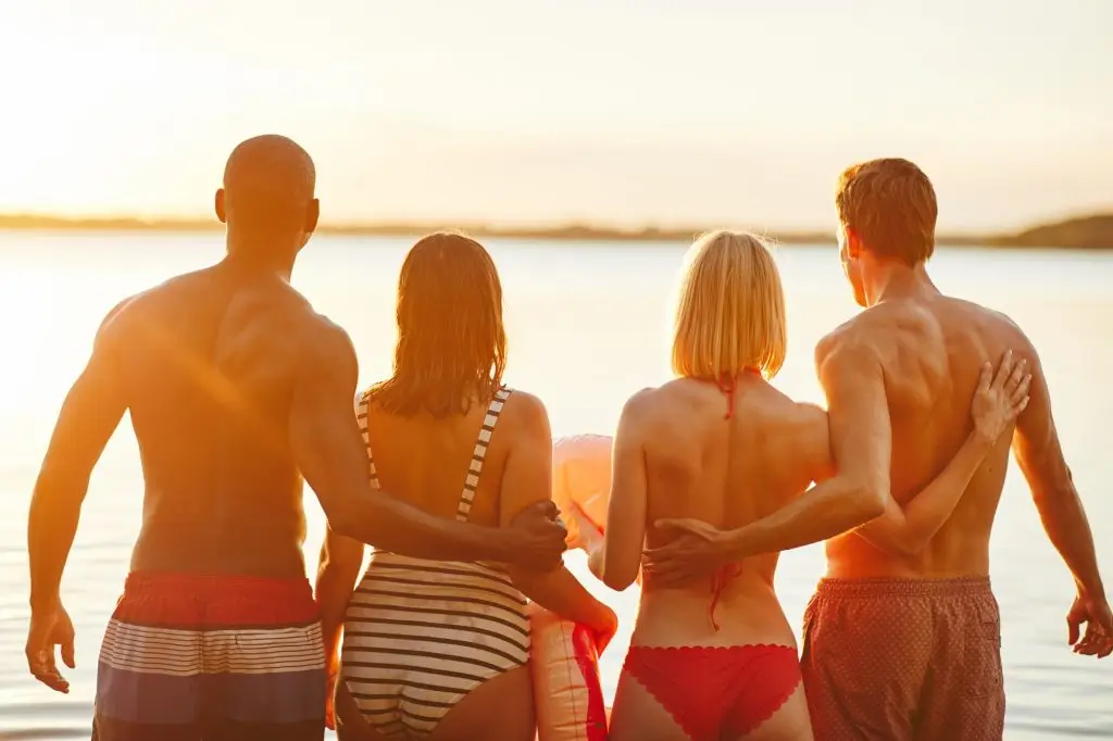 Two couples in swimwear watching the sunset over a lake of two rivers