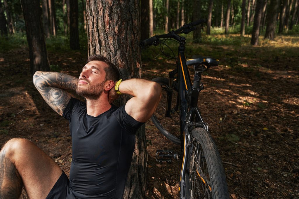 Happy male with bike relaxing in forest