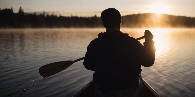 a sunset view with a man paddling in stream