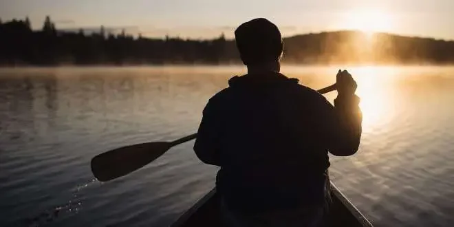 a sunset view with a man paddling in stream