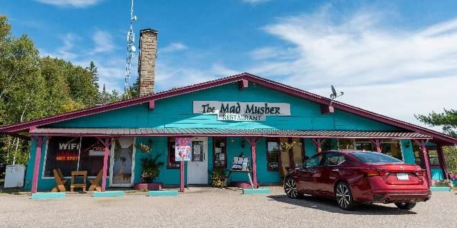 a view of the mad musher restaurant and a red car