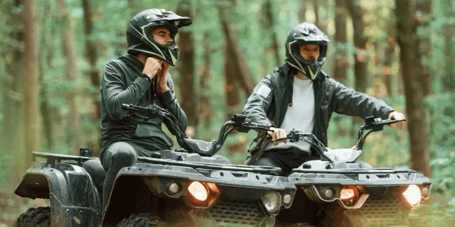 Two atv riders, speed race in forest, front view