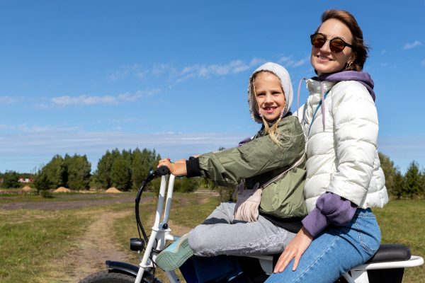 Young adult beautiful mother and daughter enjoy having fun riding electric scooter bike country